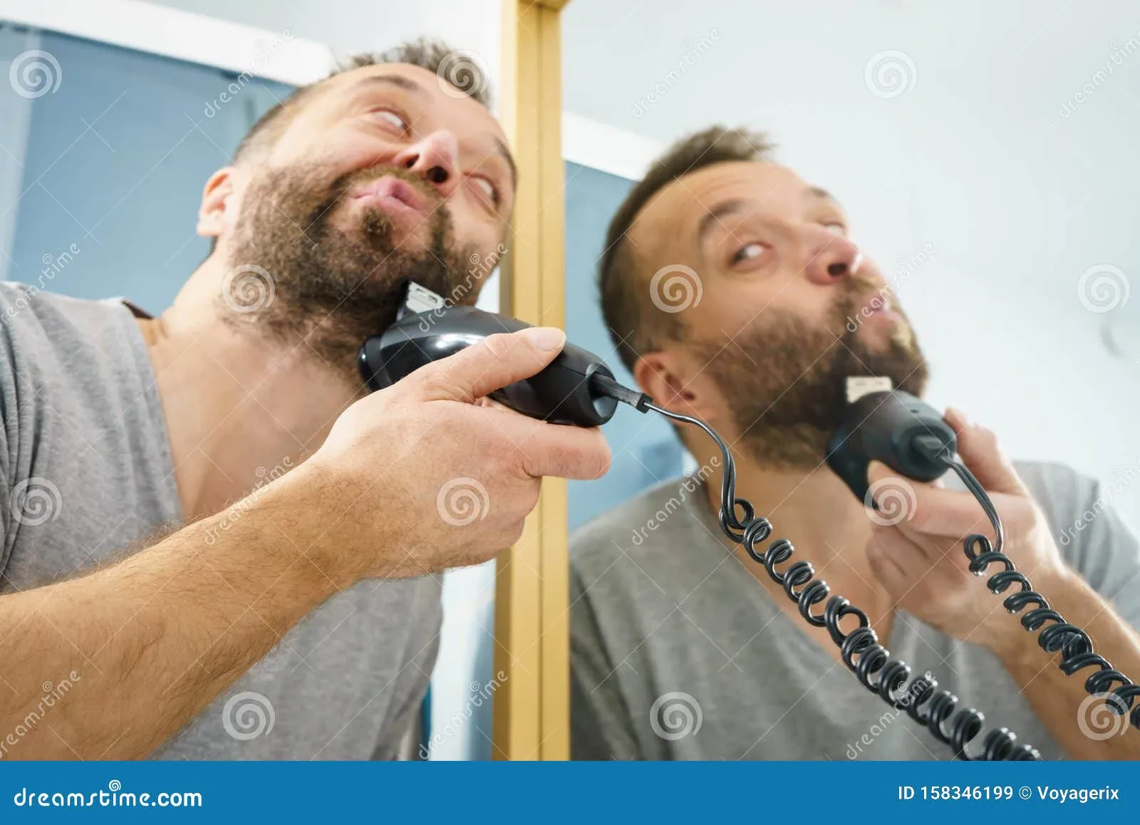Man trimming his beard with a mirror